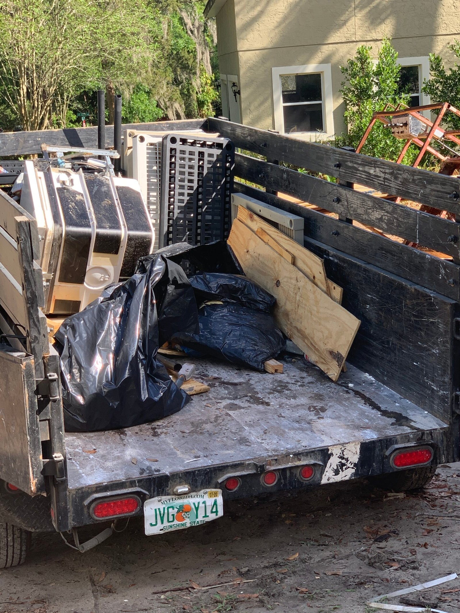 Junk Busters trailer loaded with bagged waste wood and outdoor cleanup debris