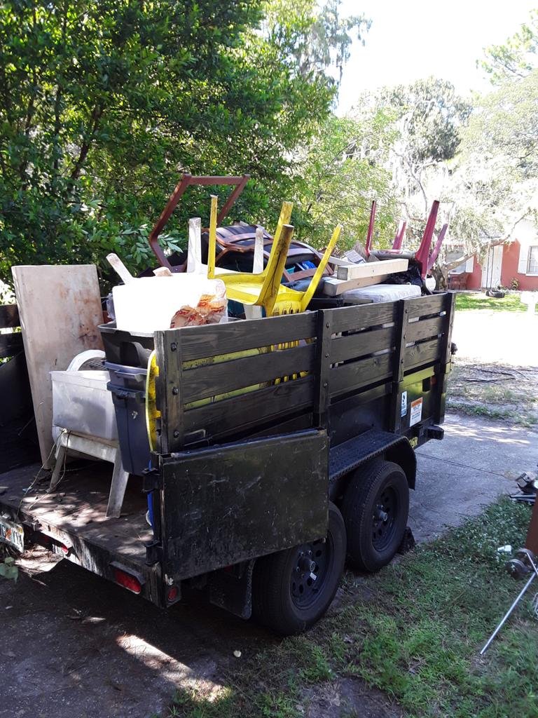 Loaded Junk Busters trailer carrying appliances furniture and household items
