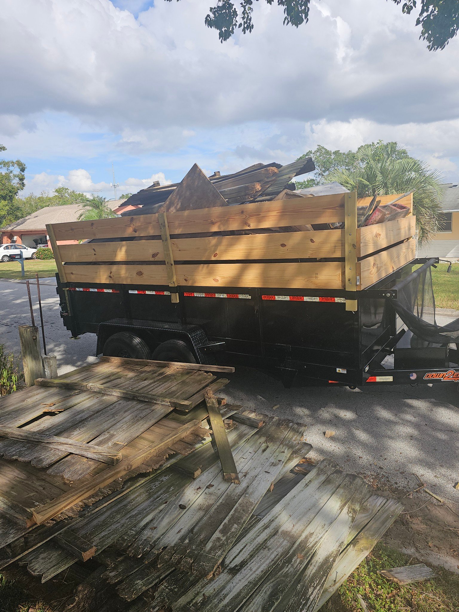 Junk Busters trailer hauling dismantled shed wood and bulky debris from a Florida property